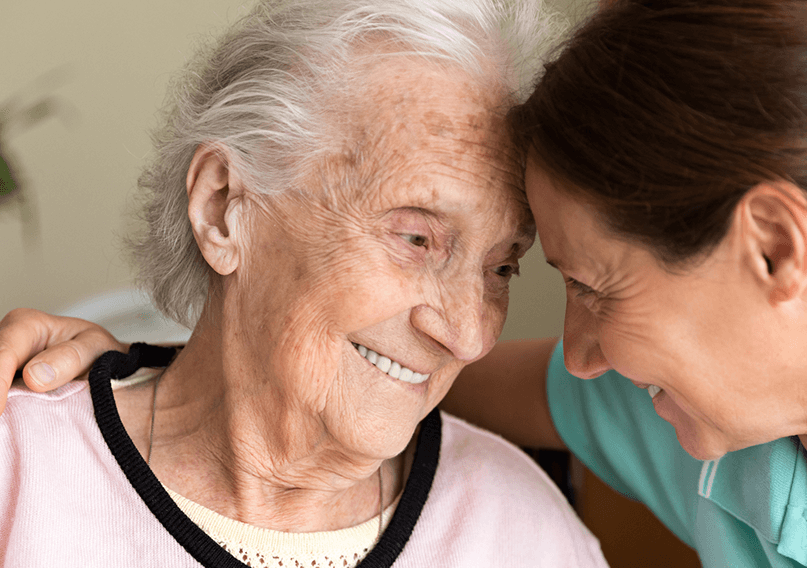 An older woman smiling with her carer